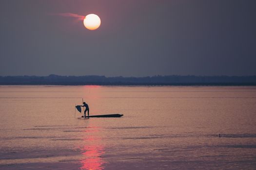 Fishermen make a living by using traps to catch fish that have nets like catching fish during the sunset.