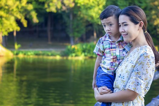 Mother and baby are happy, smiling, enjoying the warm and pure air in a beautiful garden.