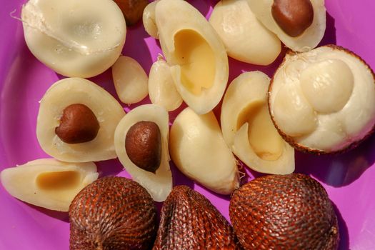 Close up of peeled, cuted and whole pieces of Snake fruit with seed. Top view of healthy fruit. Salak pondoh is one of the salak cultivars that mostly grows in Bali. Macro photo of Sweet Salacca.