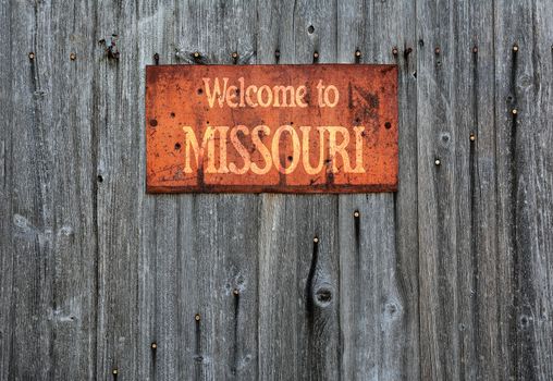 Rusty metal sign on wooden wall with the phrase: Welcome to Missouri.