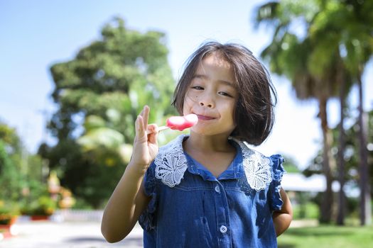 Cute little girl eating popsicle with sunset background