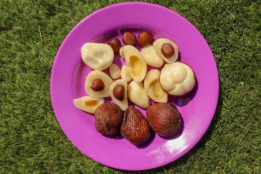 Close up of peeled, cuted and whole pieces of Snake fruit with seed. Top view of healthy fruit. Salak pondoh is one of the salak cultivars that mostly grows in Bali. Macro photo of Sweet Salacca.