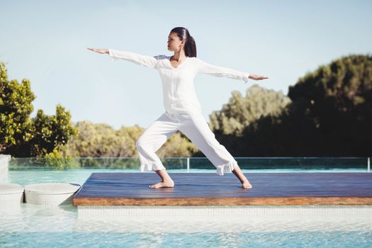 Calm brunette doing yoga by the pool