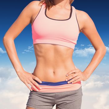 Pretty fit woman against bright blue sky over clouds