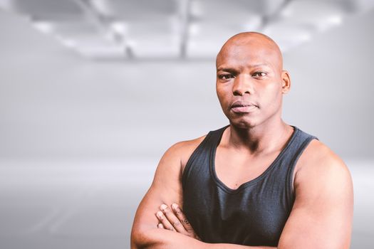 Portrait of bald bodybuilder with arms crossed against white abstract room