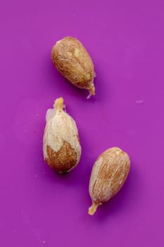 A few pieces of seed fresh red rambutan isolated on purple background. Top view of a seed of Nephelium lappaceum fruit. Rambutan seeds close-up macro, isolated.