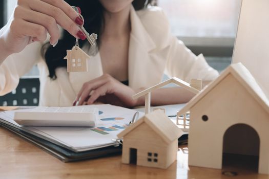 Real estate agent holding a key and asking costumer for contract to buy, get insurance or loan real estate or property.
