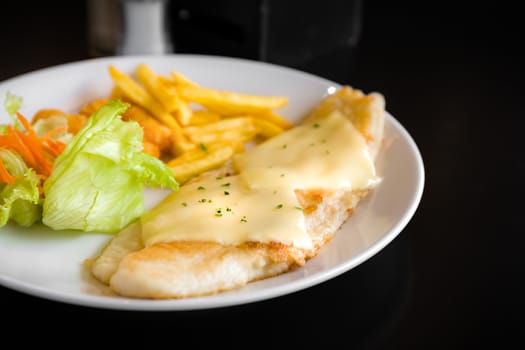 Grilled fish steak with vegetable salad and fries.