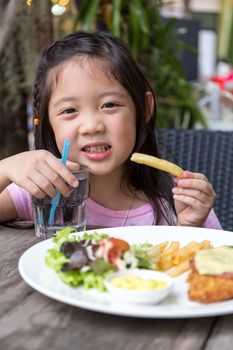 Child eating steak and fries at restaurant.