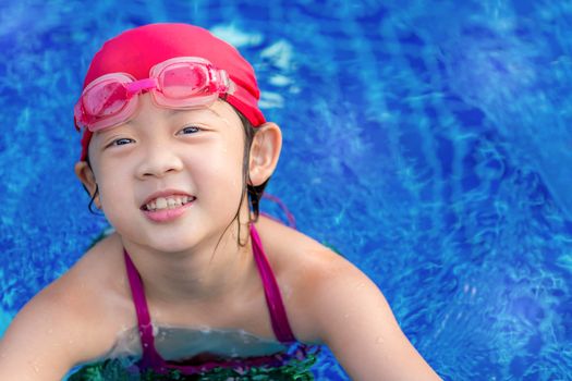 Happy smiling little girl in swimming pool.