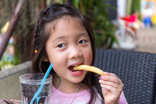 Child eating French fries and water at restaurant.