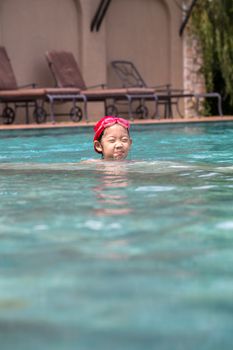 Happy child in outdoor swimming pool in afternoon.