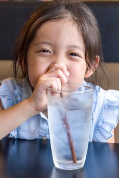 Child drinking water from glass using straw.
