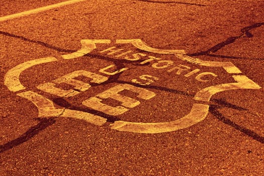 Sign on historic route 66 in the Mojave desert photographed against the sun at sunset.