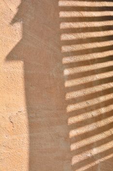 Morning sun beaming on the wall through window blinds.