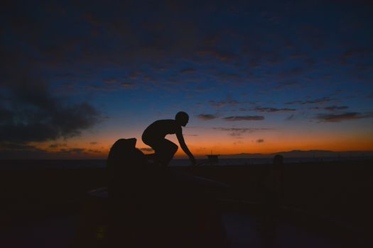 Surfing at Sunset. Young Man Riding Wave at Sunset. Outdoor Active Lifestyle.