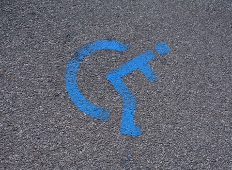 Disabled blue parking sign painted on dark asphalt.