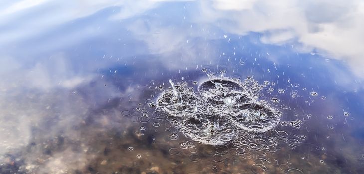 Beautiful water at a lake with splashing water and ripples on the surface with clouds and sky reflections