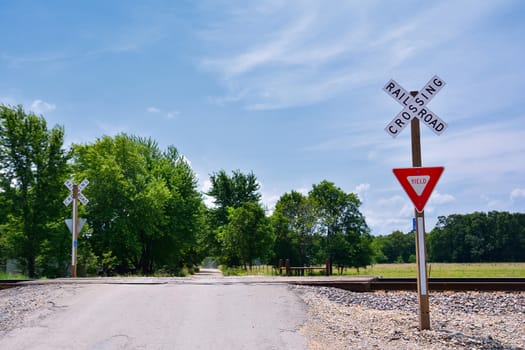 Railroad crossing sign against blue sky background, with space for your text.