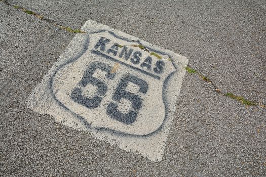 Historic Route 66 marker in Kansas on asphalt.