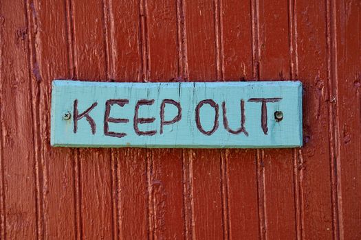 Keep out sign over old rustic wooden textured surface.