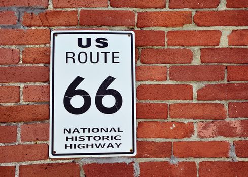 Historic US Route 66 road sign on a brick wall in Kansas.