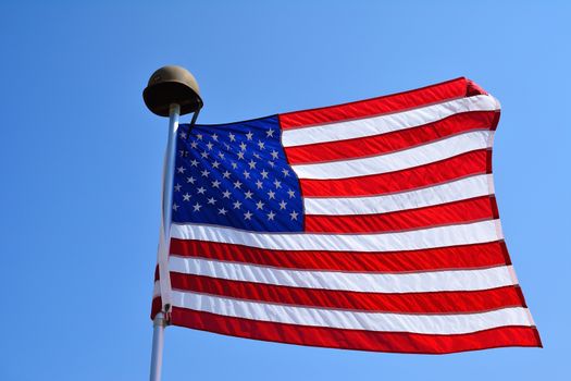 United States flag waving with a military helmet on the mast