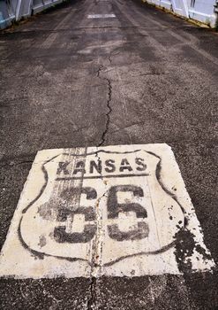 Historic Route 66 marker in Kansas on asphalt.