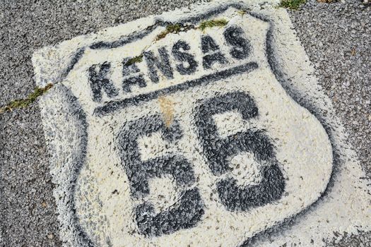 Historic Route 66 marker in Kansas on asphalt.