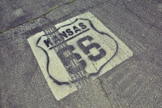 Historic Route 66 marker in Kansas on asphalt.