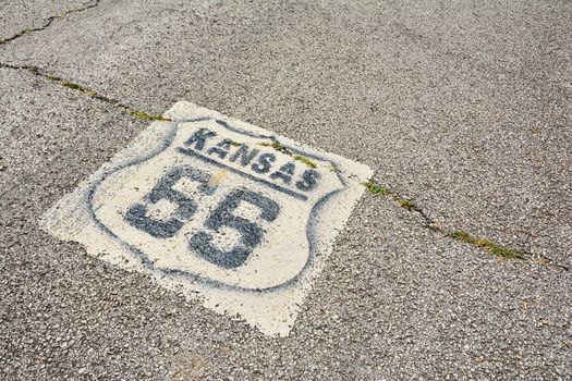 Historic Route 66 marker in Kansas on asphalt.