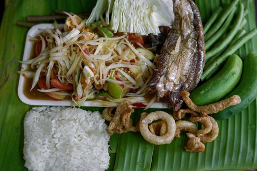 Isan Thai food Name papaya salad, pickled fish, salted egg With various machines Green banana leaf background