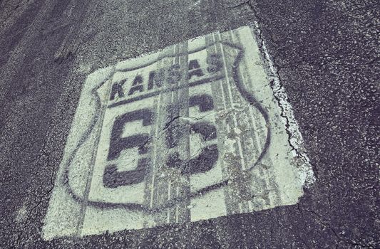 Historic Route 66 marker in Kansas on asphalt.