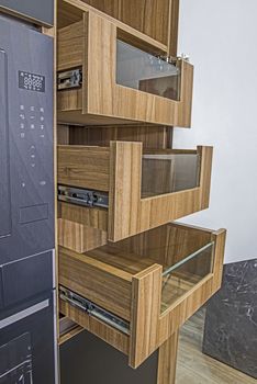 Interior design decor of kitchen in luxury apartment showing closeup detail of open cupboard with sliding wooden shelves