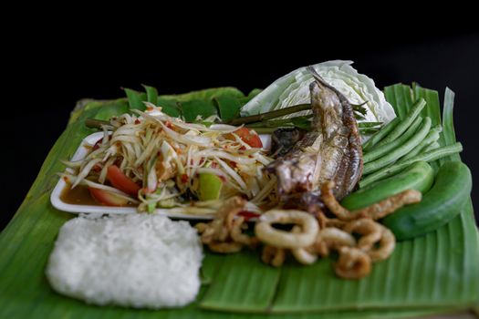 Isan Thai food Name papaya salad, pickled fish, salted egg With various machines Green banana leaf background