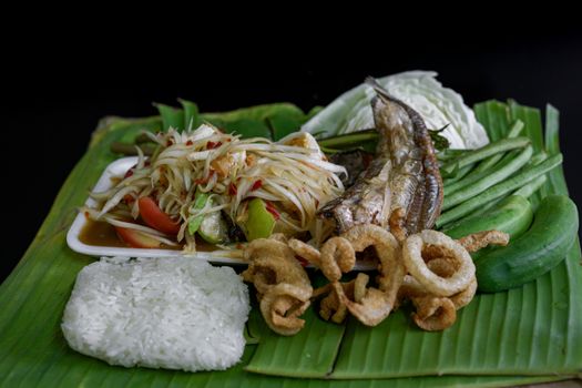 Isan Thai food Name papaya salad, pickled fish, salted egg With various machines Green banana leaf background