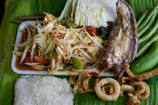 Isan Thai food Name papaya salad, pickled fish, salted egg With various machines Green banana leaf background