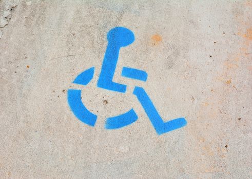 Disabled blue parking sign painted on asphalt.
