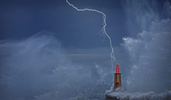 Lightning and wave over old lighthouse and pier of Viavelez in Asturias, Spain.