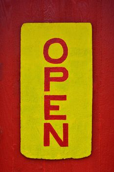 A rustic wooden "open" sign in red and yellow.