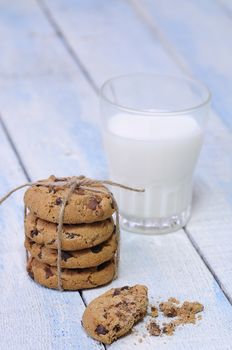 Stack of chocolate chip cookies with glass of fresh milk on blue wooden table