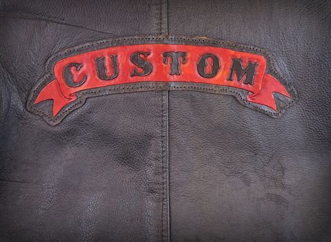 Red custom label on back of leather jacket in close-up.