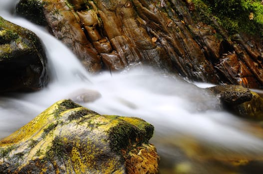 Long exposure shot of waterfall between stones covered with moss