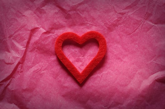Red heart on pink paper.From above