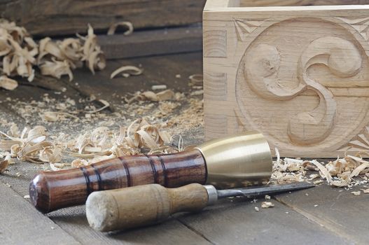 Chisel and hammer near beautiful wooden box with decor on floor