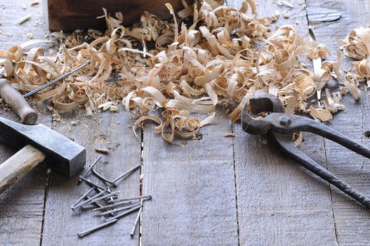 Spiral wooden chips with pincers, hammer, awl and nails on wooden floor