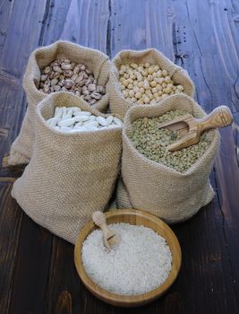 Different kind of peas in textile bags and white rice in bowl