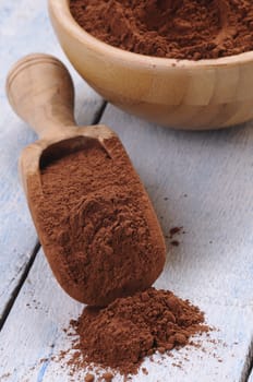 Wooden spoon of cocoa on table