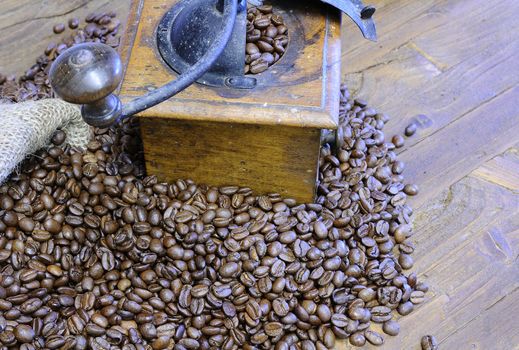 Scattered coffee beans and retro grinder on wooden table