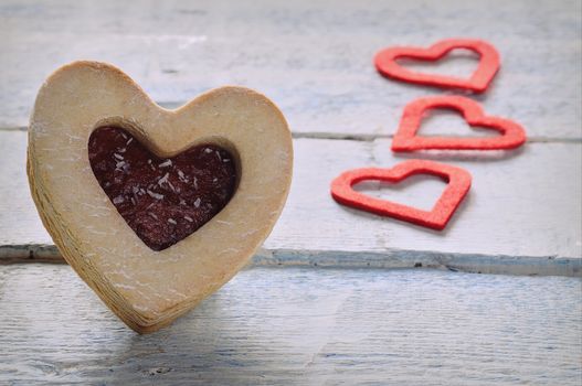 Close-up of cookie with jam and three red paper hearts